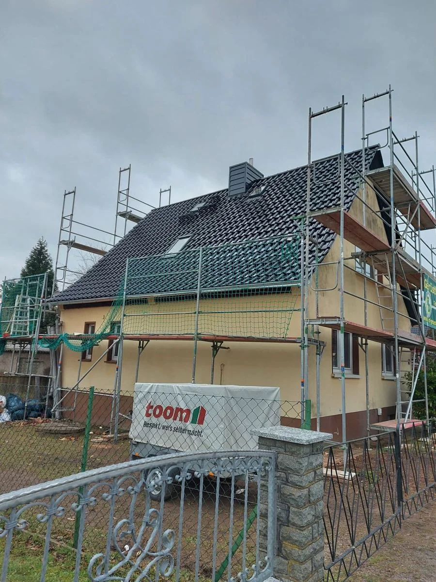 Haus mit neuem schwarzem Ziegeldach, das Gerüst steht noch